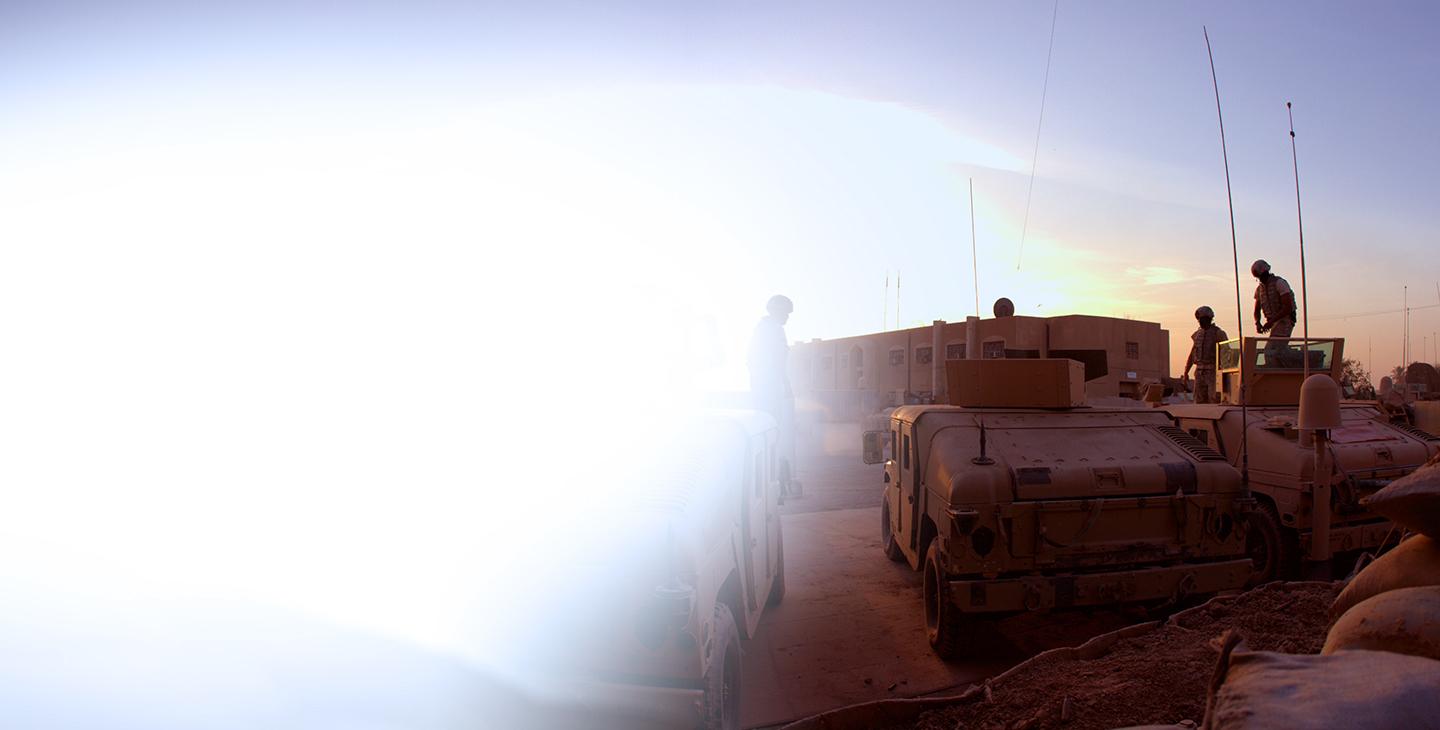 Military vehicles parked at a base at dusk